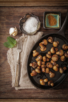 fried mushrooms with salt and pepper on a wooden background