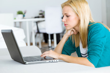 Pretty young woman working with laptop at home.