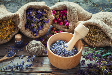 Healing herbs in hessian bags, wooden mortar with dry lavender,