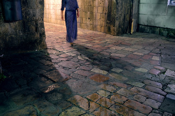 Blurred silthouette of a girl, going from a stone arch
