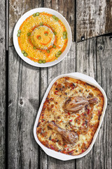 Oven Baked Vegetable Stew with Chicken Meat, and Bowl of Garnished Russian Salad, on Old Floorboards Surface.