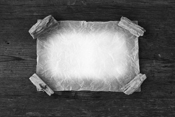 The paper crumpled leaf is pressed by stones to an old granary board. Black and white photo. Free...