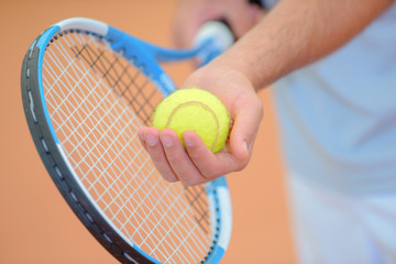 Closeup of hands holding tennis racket and ball, poised to serve
