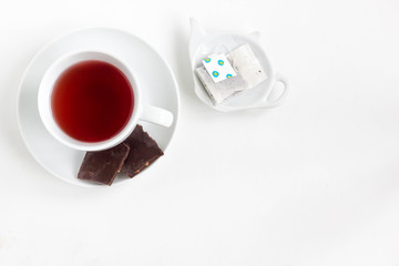 Fruit tea in white cup with chocolate. White background, top view.
