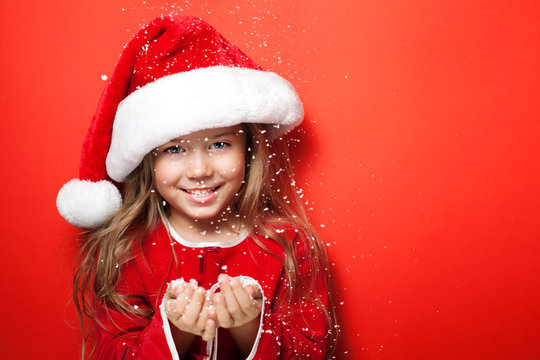 Happy girl in Christmas cap  under the snow