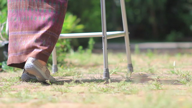 Elderly woman using a walker in backyard