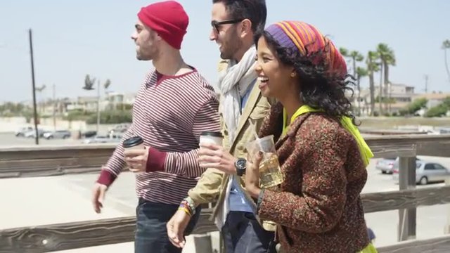 Multi ethnic friends enjoying spring break walking on a pier at the beach