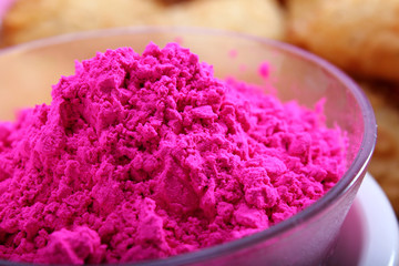 holi color in bowl with blurred gujiya snacks