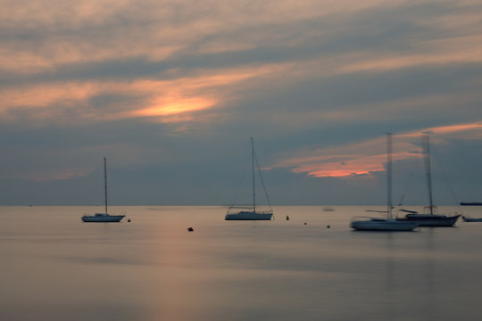 Fototapeta Sailboats on open sea in a summer at sunset time