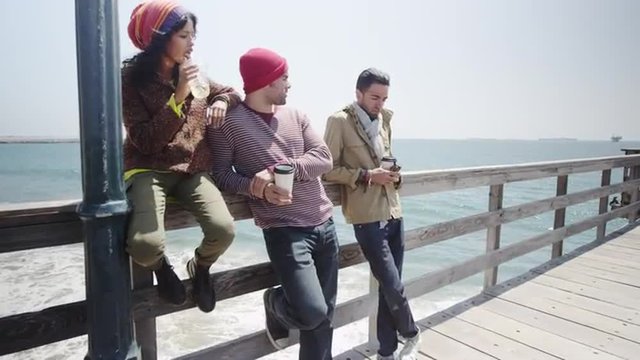 Group of young multi ethnic friends hanging out on a pier on a bright sunny day
