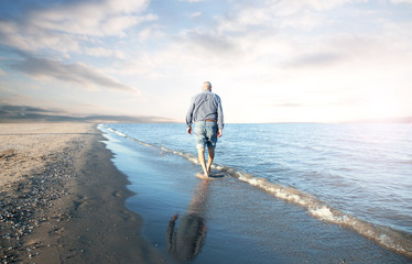 solitary old man walking on the beach