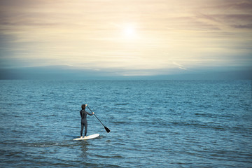 man paddling on a board at the sea at sunset