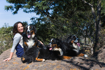 Naklejka na ściany i meble Frau sitzt mit ihren Hunden auf Stein im Wald