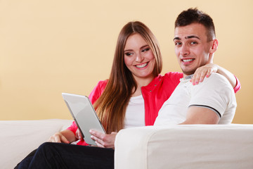 couple with tablet sitting on couch at home