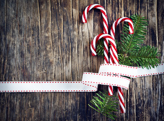 Candy cane with white and red ribbon on wooden background