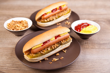 Zwei Hotdogs mit Gurke, Zwiebeln, Ketchup und Senf