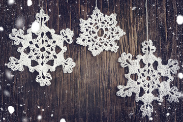 Crocheted white snow flakes on wooden background