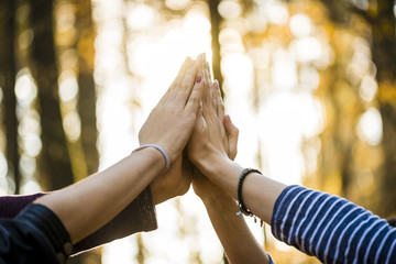 Closeup view of four people joining their hands together high up