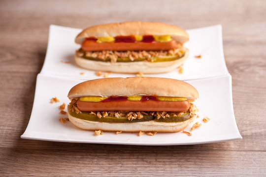 Zwei Hotdogs mit Gurke, Zwiebeln, Ketchup und Senf