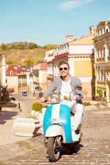 Handsome cute man with glasses riding a scooter on the street