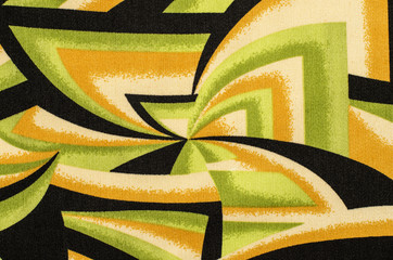 Abstract shapes pattern on fabric. Green with black and yellow geometric spyral shapes material as...