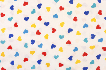 Hearts pattern on white fabric. Blue, yellow and red hearts print as background.