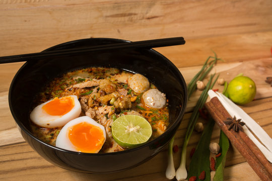 bowl of noodles with vegetables and soft boiled egg on wooden ta
