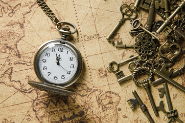 Fototapeta na wymiar vintage pocket watch and skeleton key on ancient map background