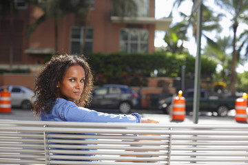 Woman sitting on a bus bench looking over shoulder