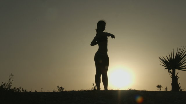 Silhouette of young woman stretching before doing exercises early in the morning