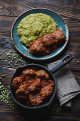 Meatballs in tomato sauce served with green peas