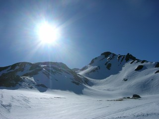 Beautiful idyllic snowy winter landscape in a mountain ski resort, on a crisp sunny morning. Rocky mountain peaks.