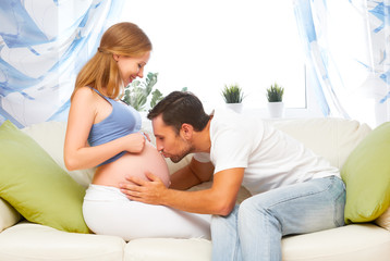 happy family in anticipation of birth of baby. man kissing belly