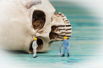 Miniature worker working on old skull,selective focus