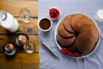 chocolate pancakes on a wooden table. ripe currants and fresh mi
