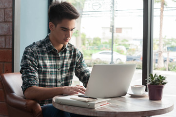 Businessman using laptop with tablet and pen on wooden table in