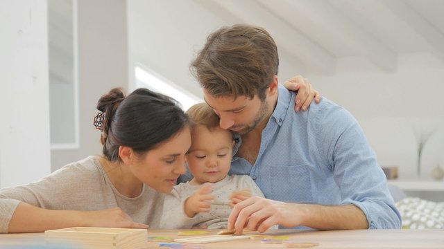 Parents with baby girl playing with wooden game