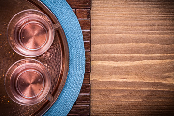Table cloth coppery tray tea cups on wooden board