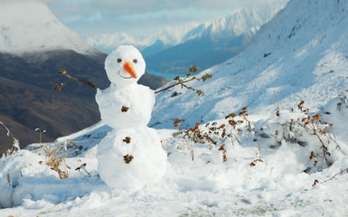 Happy snowman in mountains.