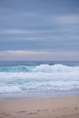 Fototapeta na wymiar Wave crashing on a coast in Nazare, Portugal.