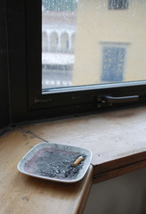 Fototapeta na wymiar Ashtray on Cold Window Ledge