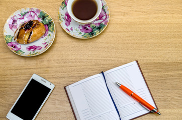 Cup of tea with notepad on wooden background top view