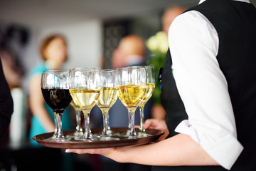 Waitress with dish of champagne and wine glasses