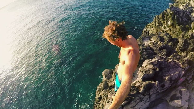 POV Slow Motion Sunset Cliff Jumping. Athletic Young Man Jumping From Cliff Into Ocean. Adventure Extreme Sports Lifestyle Hobby Vacation