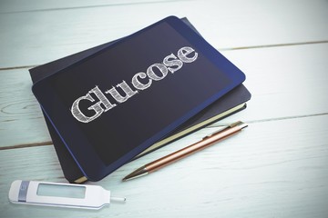 Glucose against view of a book and tablet lying on desk