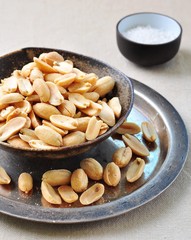 Peeled peanuts in a sea salt on an iron tray