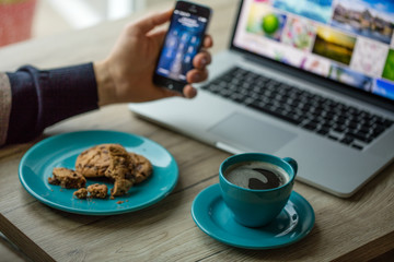 Man working on notebook, with a fresh cup of coffee and cell phone.