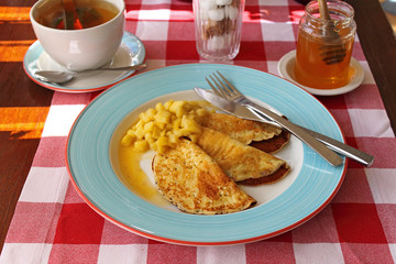 rolled pancakes on a plate with honey and powdered sugar