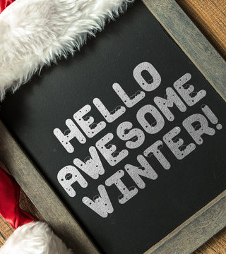 Hello Awesome Winter written on blackboard with santa hat