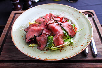 salad of meat on a plate, cut into thin slices
